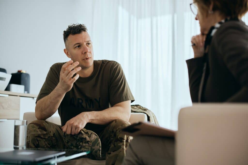 Worried soldier communicating with psychotherapist during mental health therapy session.